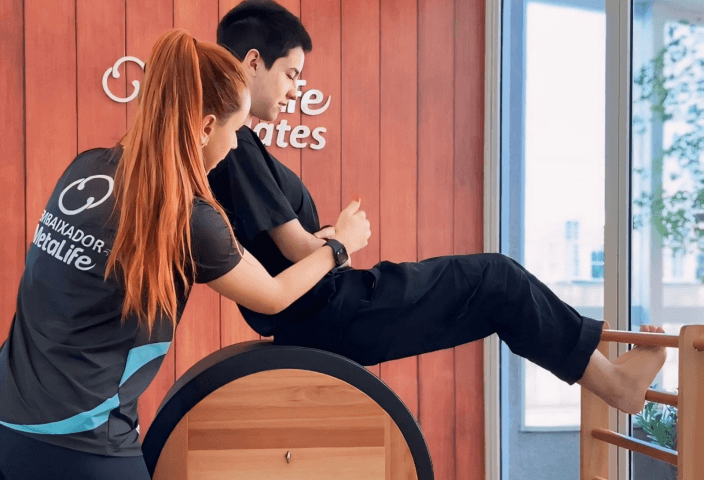 Instrutora ajudando em exercício de pilates no aparelho.